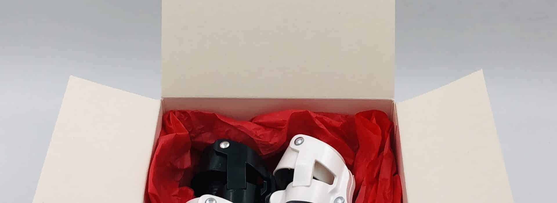 Coffret ouvert contenant quatre bouchons compacts blancs et noirs posés sur papier de soie rouge