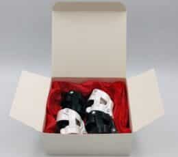 Coffret ouvert contenant quatre bouchons compacts blancs et noirs posés sur papier de soie rouge